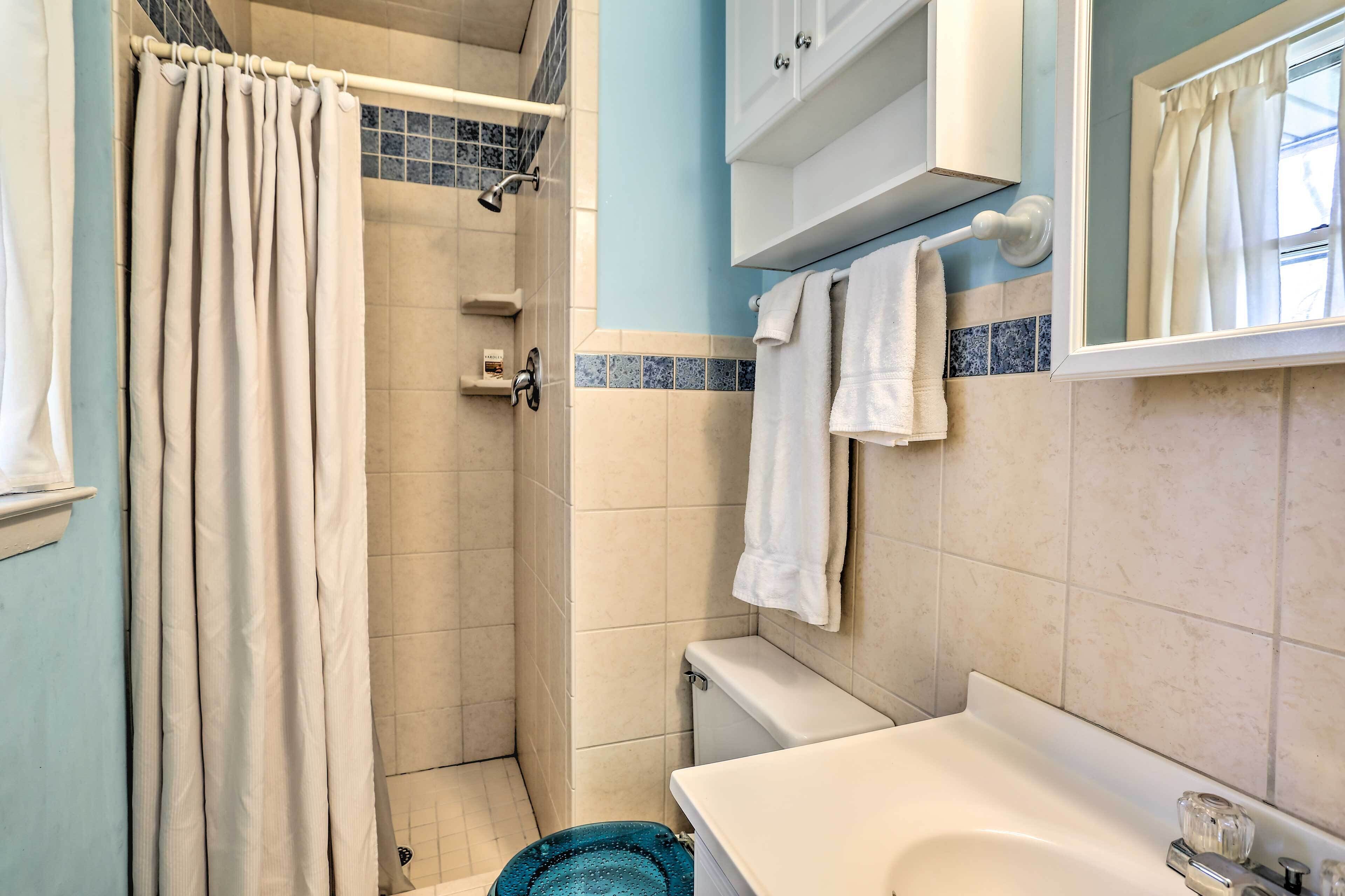 A bathroom with a shower, toilet, sink, and a towel rack.