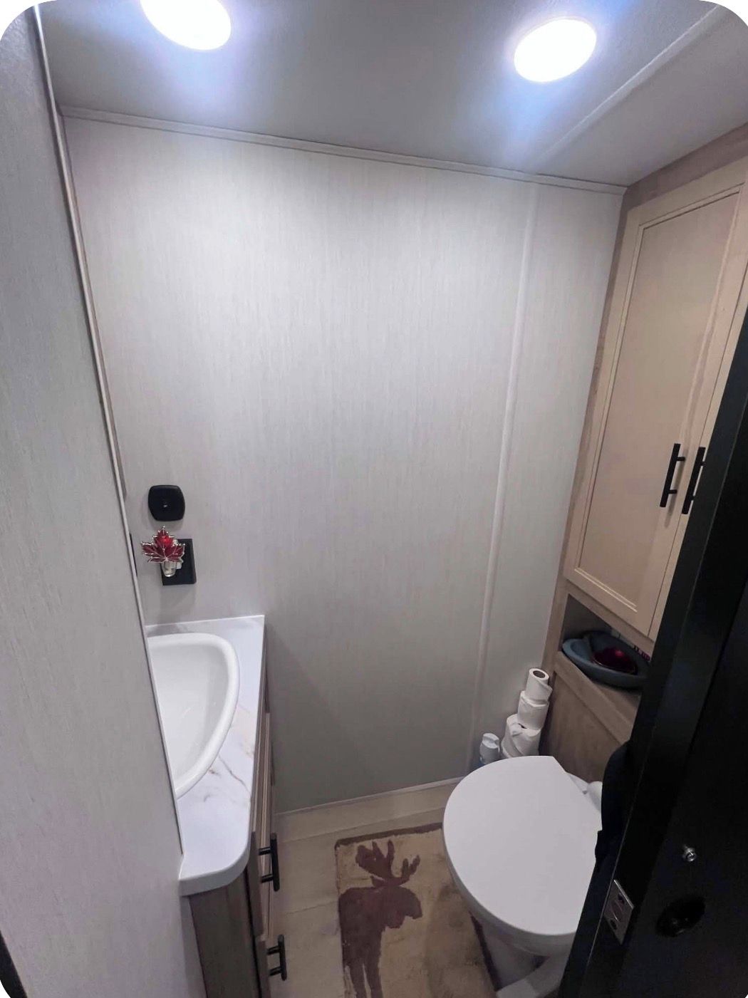 Ein kleines Badezimmer mit Toilette, Waschbecken und Schrank.