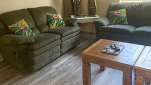 A living room with two green sofas, a wooden coffee table, and a lamp. - Cozy, comfortable and convenient (Pensacola)