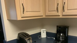 A kitchen with a toaster, a coffee maker, and a power strip on a blue countertop. - Cozy, comfortable and convenient (Pensacola)