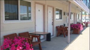 A motel with outdoor seating, numbered doors, and potted flowers. - Red Coat Inn (Fort Macleod)