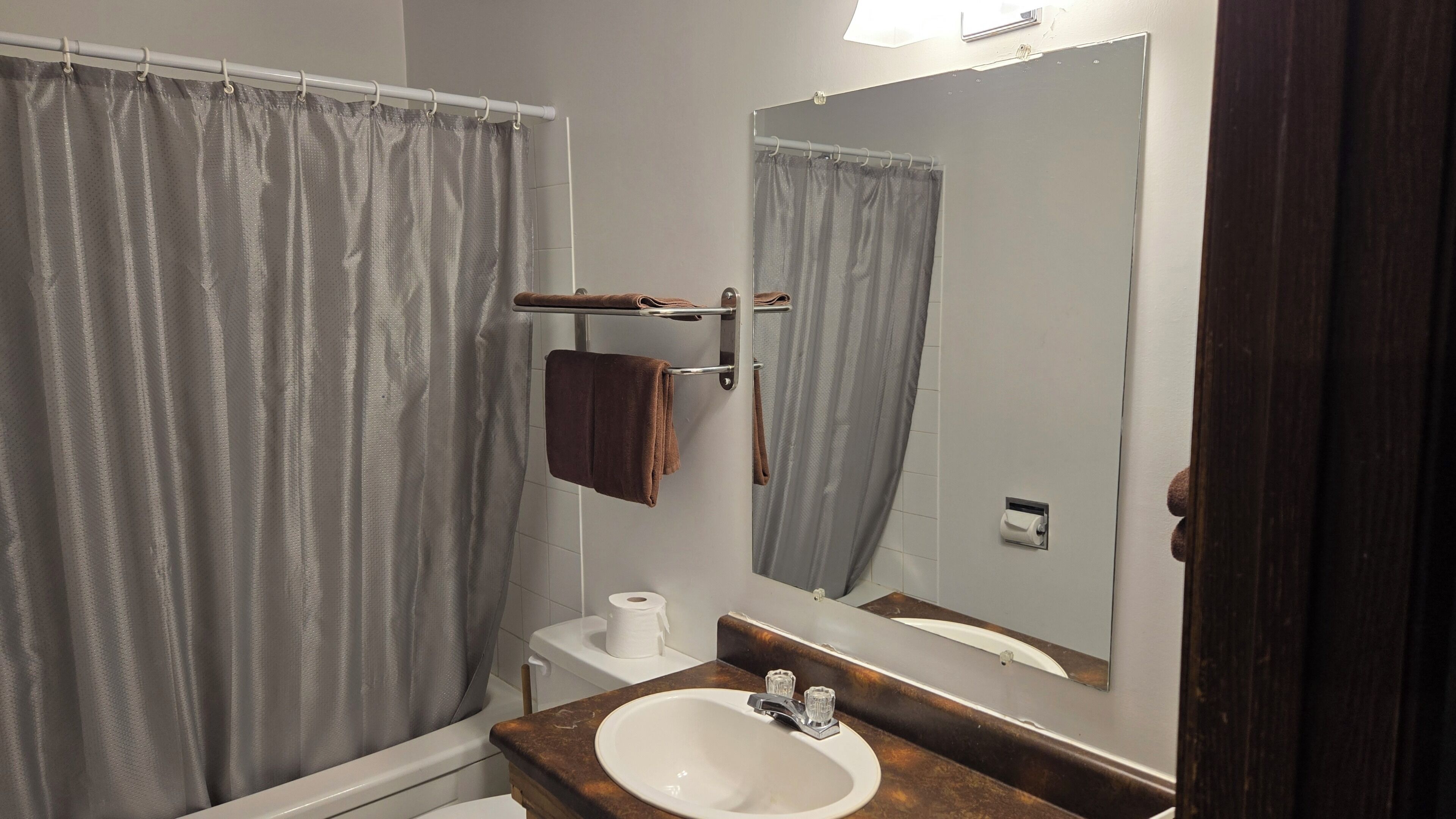 A bathroom with a bathtub, a toilet, a sink, a towel rack, and a mirror.