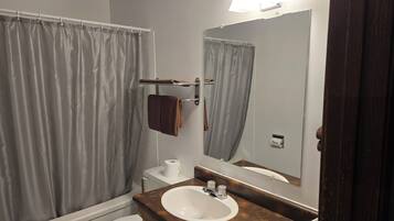 A bathroom with a bathtub, a toilet, a sink, a towel rack, and a mirror.