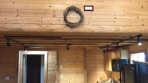 A rustic cabin interior with a wooden ceiling, a ceiling fan, a coiled rope hanging on the wall, a wooden table, a bench, a refrigerator, and a microwave. - Authentic Fairbanks log house with bathroom, kitchen, and screened front porch (Fairbanks)