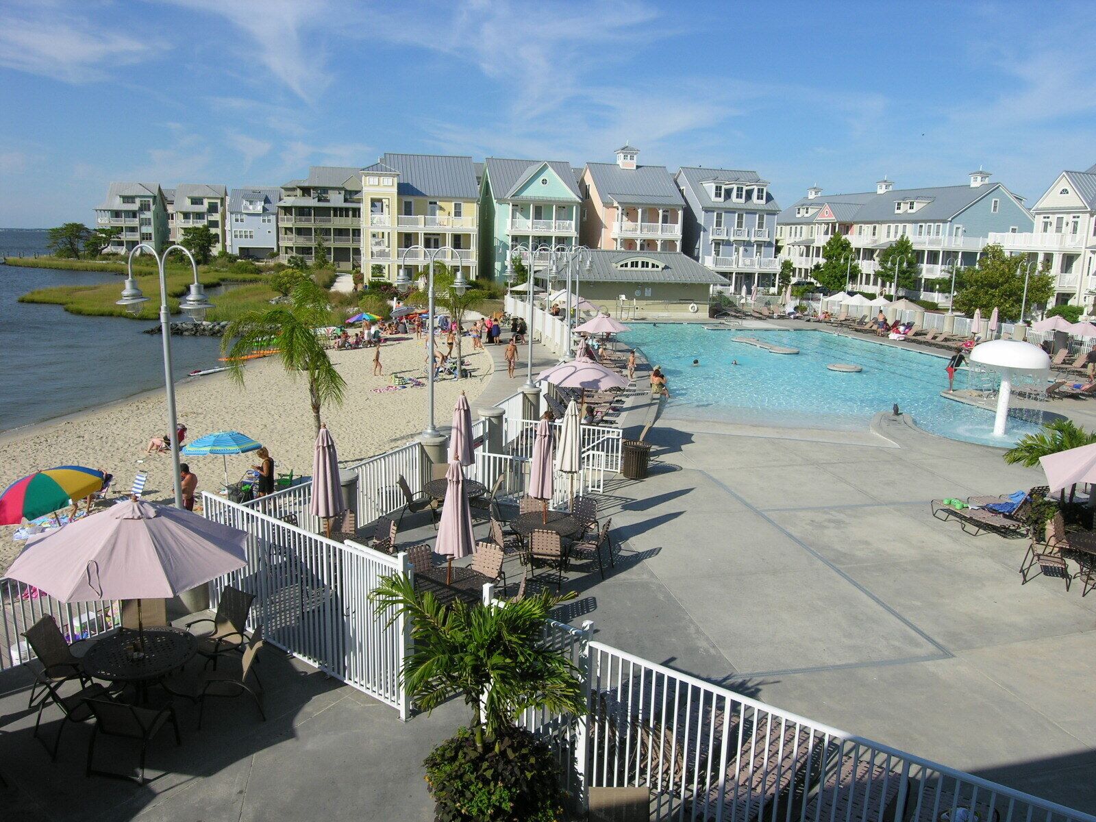 A resort with a swimming pool, beach area, and multiple buildings with balconies.