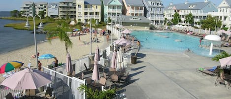 A resort with a swimming pool, beach area, and multiple buildings with balconies.