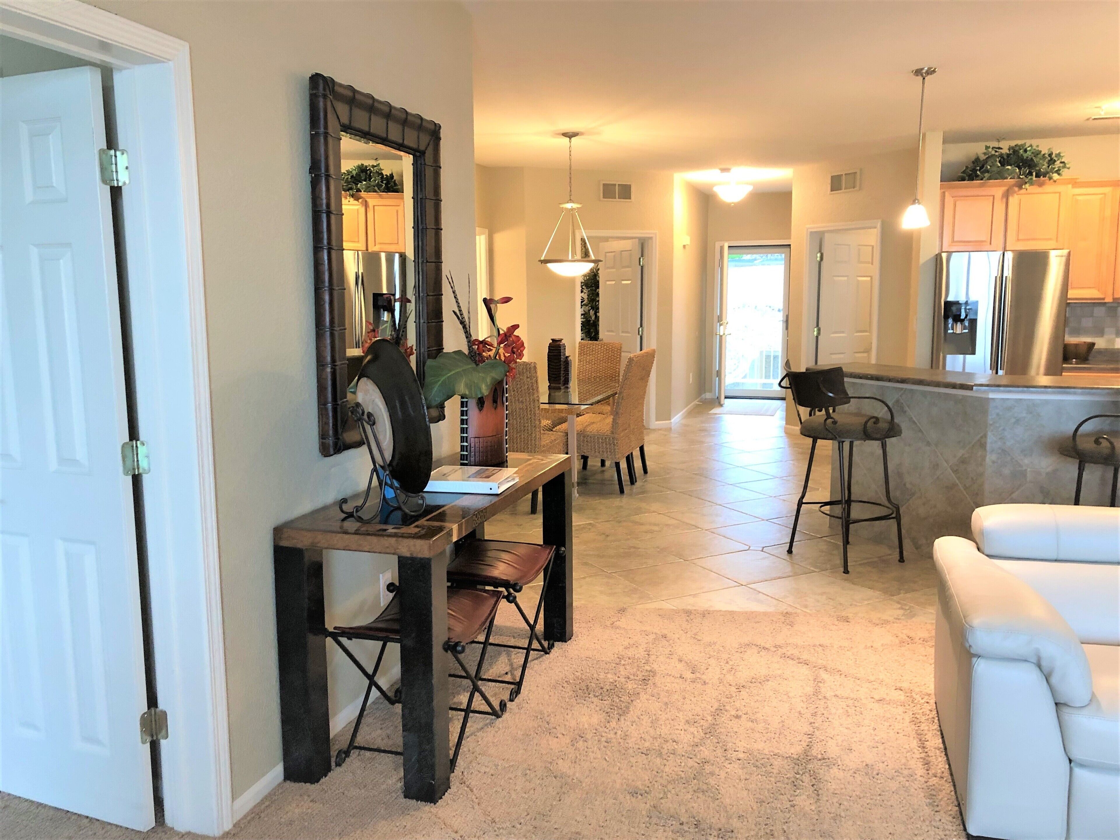 A spacious kitchen with a dining area, a white sofa, and a large mirror.
