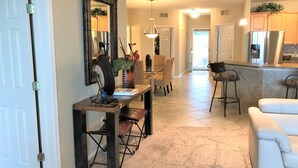 A spacious kitchen with a dining area, a white sofa, and a large mirror.