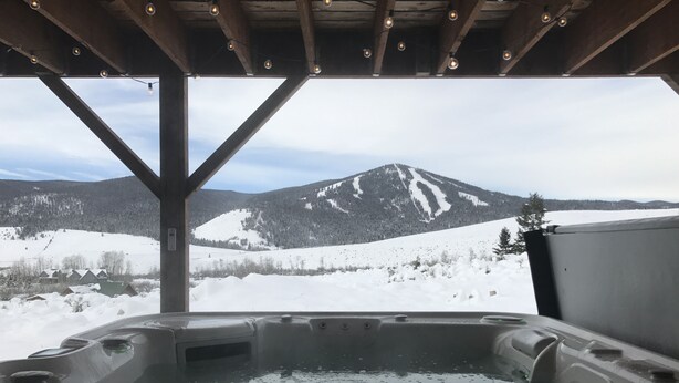 A hot tub with a view of snow-covered mountains.