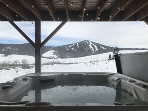 A hot tub with a view of snow-covered mountains.