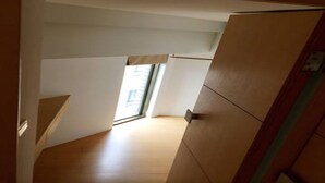 A narrow stairway leading to a room with a window, wooden flooring, and a door with a green stripe. - Cozy place in the hub of Taipei city (Taipei)