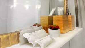 A bathroom vanity with a white marble countertop, a white sink, and a wooden cabinet with a potted plant. - Cozy place in the hub of Taipei city (Taipei)
