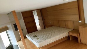 A compact room with a single bed, wooden paneling on the walls, a small wooden bench, and a radiator. - Cozy place in the hub of Taipei city (Taipei)
