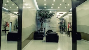 A modern lobby with a reception desk, seating area, and potted plants. - West Insula Units By AYS (Quezon City)