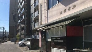 A building with a sign reading "LITTLE ASIA GUEST HOUSE" and a red banner above the entrance. - Kagoshima Little Asia - Hostel (Kagoshima)