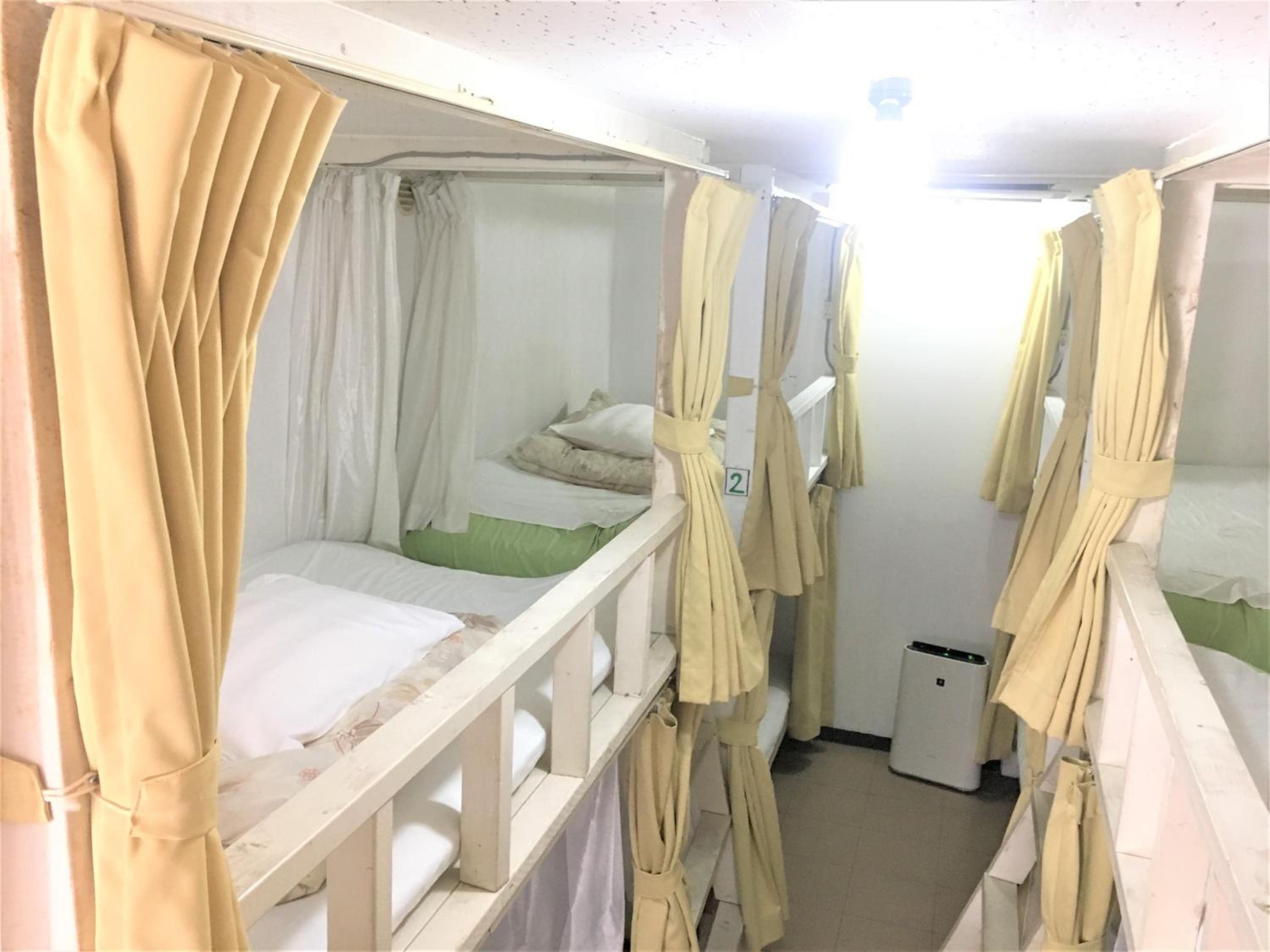 Habitación tipo dormitorio con literas, un cubo de basura pequeño y un número en la pared.