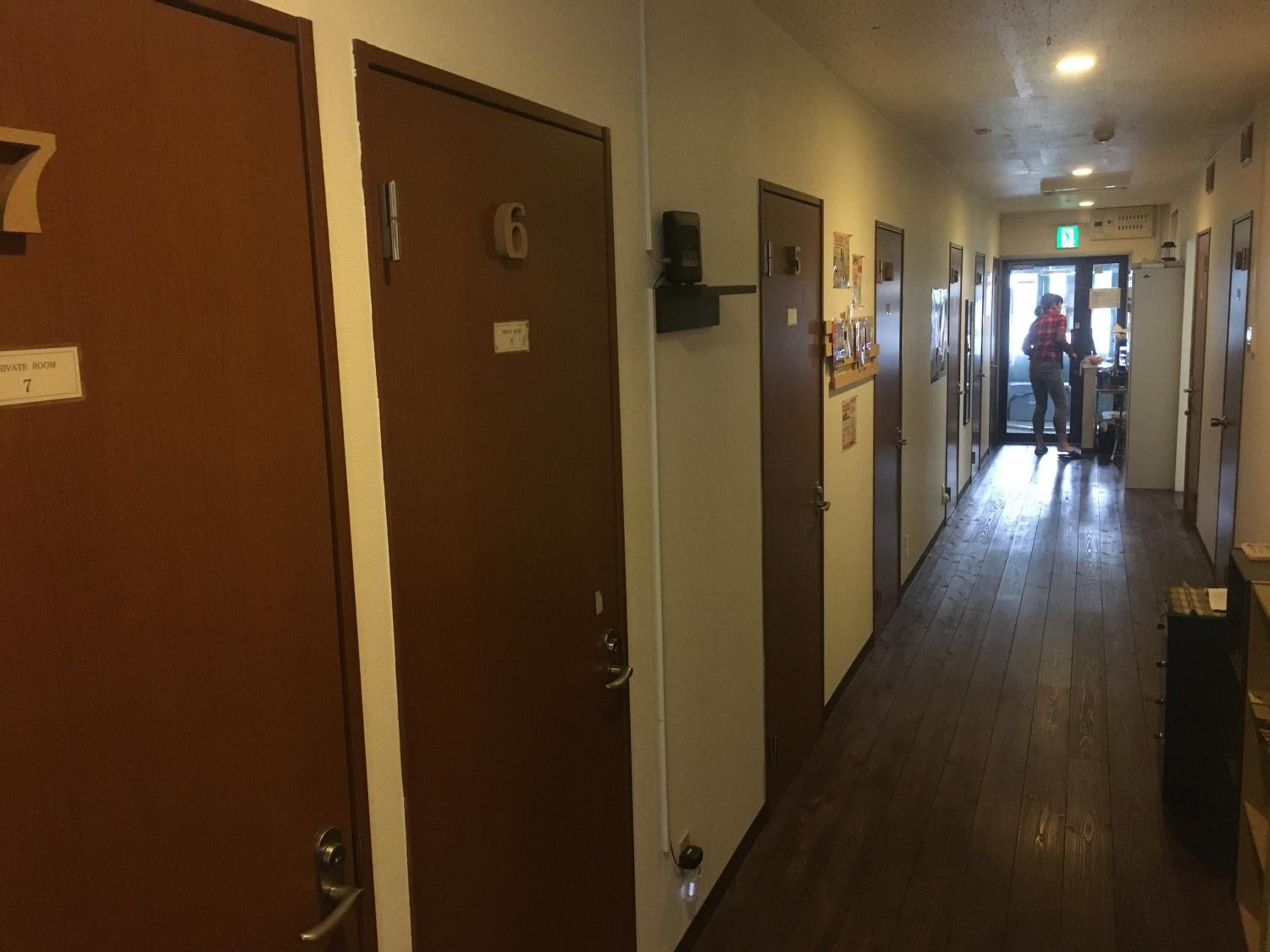 Pasillo de hotel con puertas numeradas 6 y 7, un cartel de habitación privada y una persona a lo lejos.