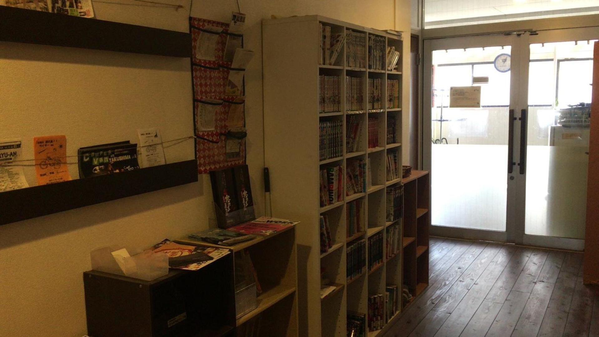 A library interior with bookshelves, a bulletin board, and a door leading outside.