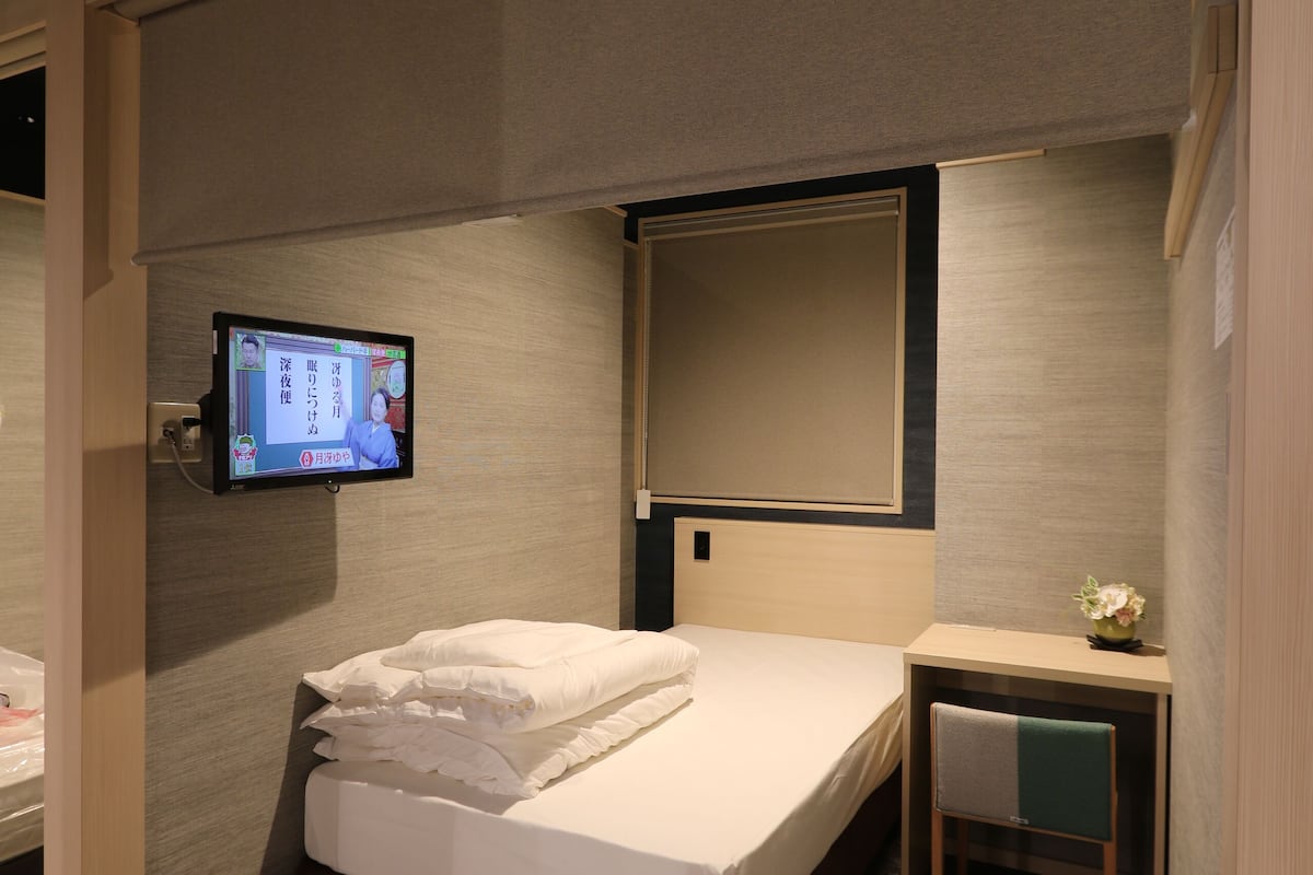 A hotel room with a bed, a desk, a television, and a mirror.