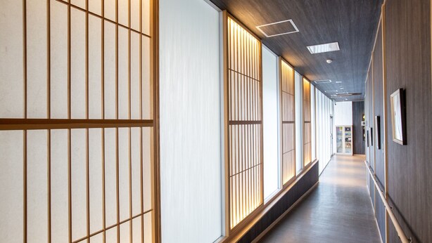 A corridor with sliding doors and a wooden floor, leading to a room with a bed and a nightstand. - HOTEL J-SHIP OSAKA NAMBA (Osaka)