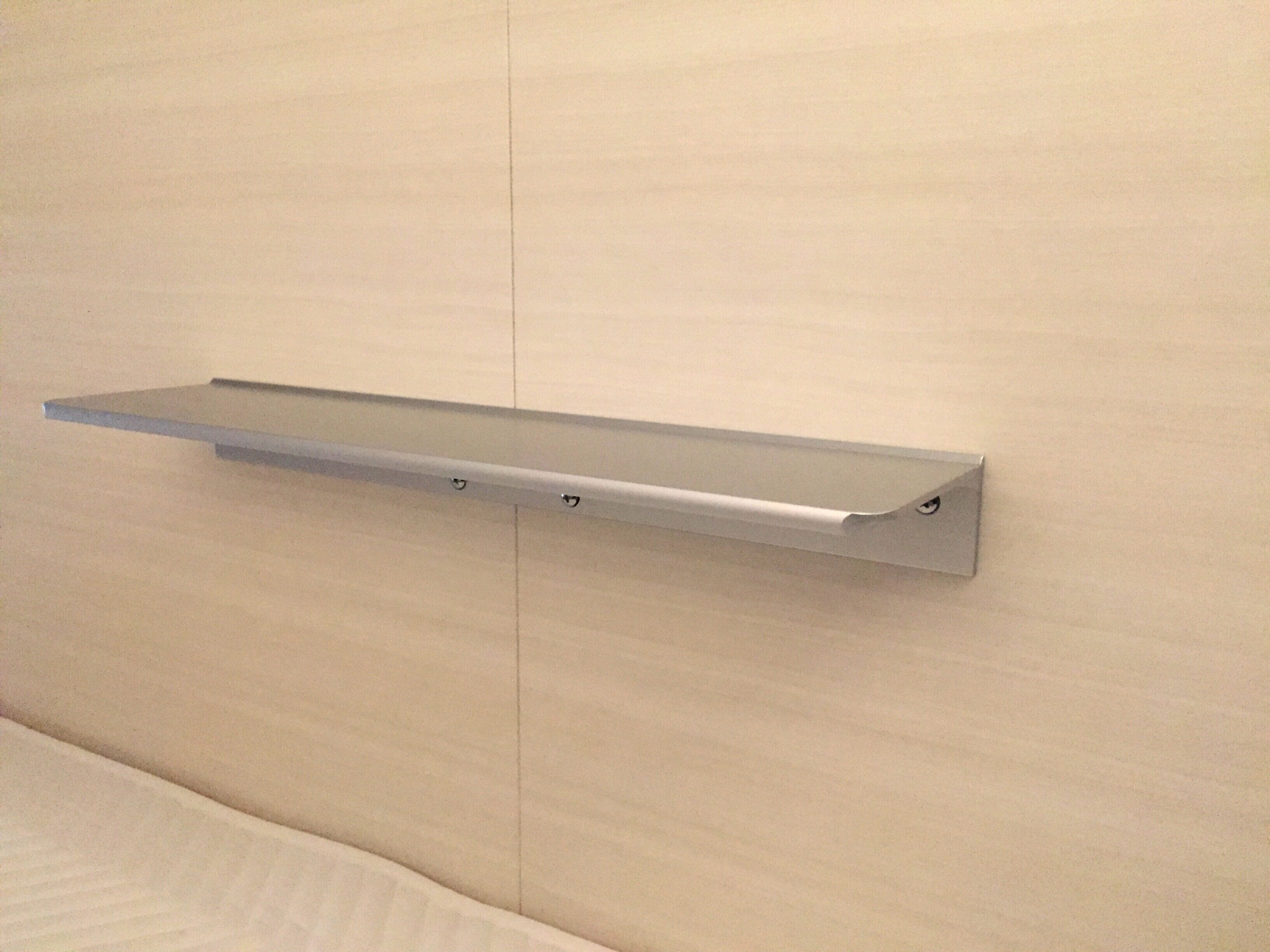 A metal shelf mounted on a beige wall.