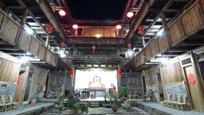 A traditional wooden building with a central open space, wooden benches, and potted plants. - Nanjing Tulou Qingdelou Inn (Zhangzhou)
