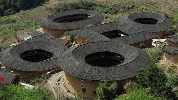 A traditional village with circular-roofed buildings surrounded by terraced fields. - Nanjing Tulou Qingdelou Inn (Zhangzhou)