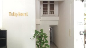 Un couloir avec une enseigne indiquant « Hôtel Tulip », une plante en pot et une chaise en bois.