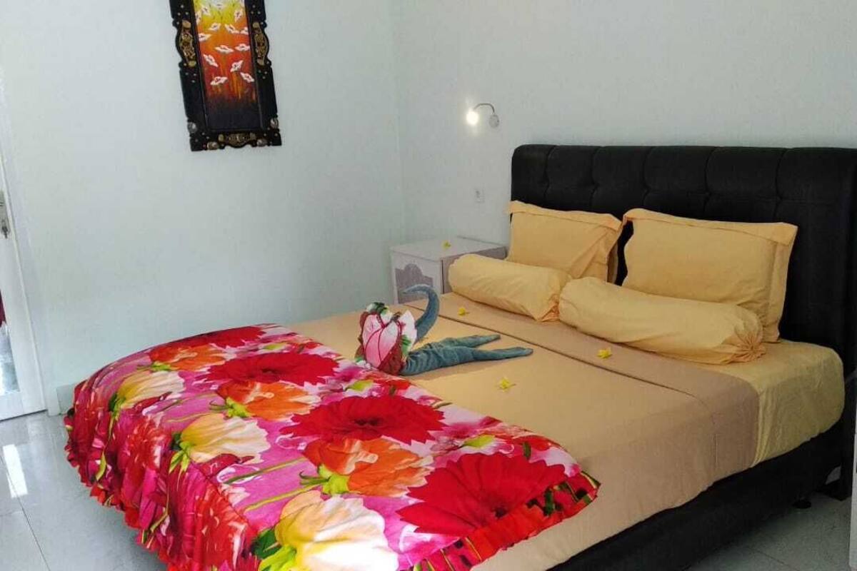 A bedroom with a bed, a nightstand, a dresser, and a wall-mounted light fixture.