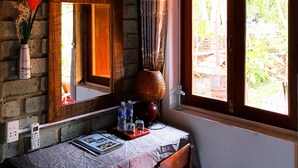 Quarto com uma mesa de madeira, um espelho, um vaso com plantas secas e uma janela com cortinas.
