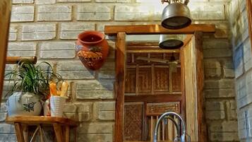A rustic kitchen with a wooden sink, a hanging light fixture, and a brick wall.