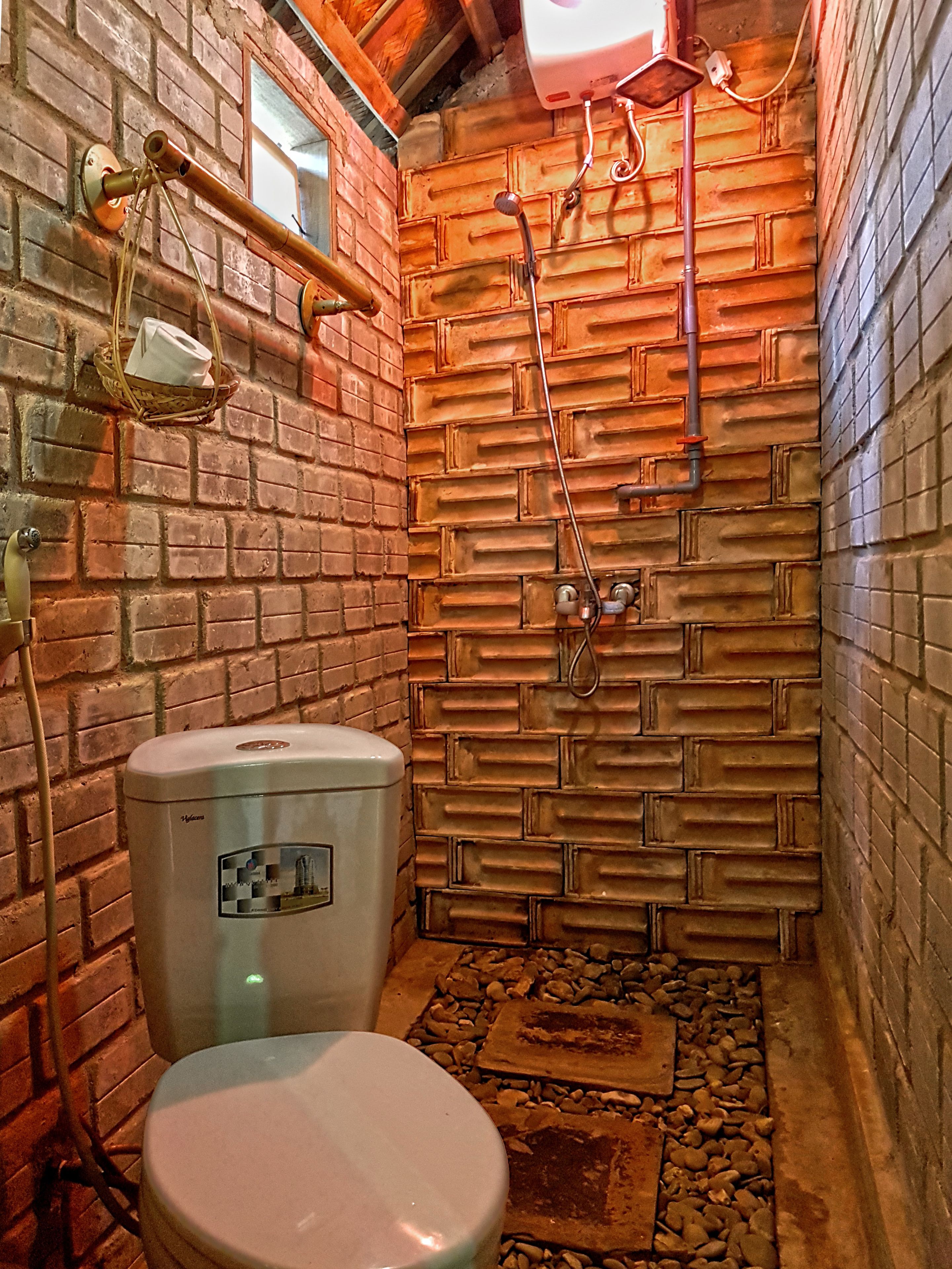 Un baño con inodoro, ducha y pared de ladrillo.