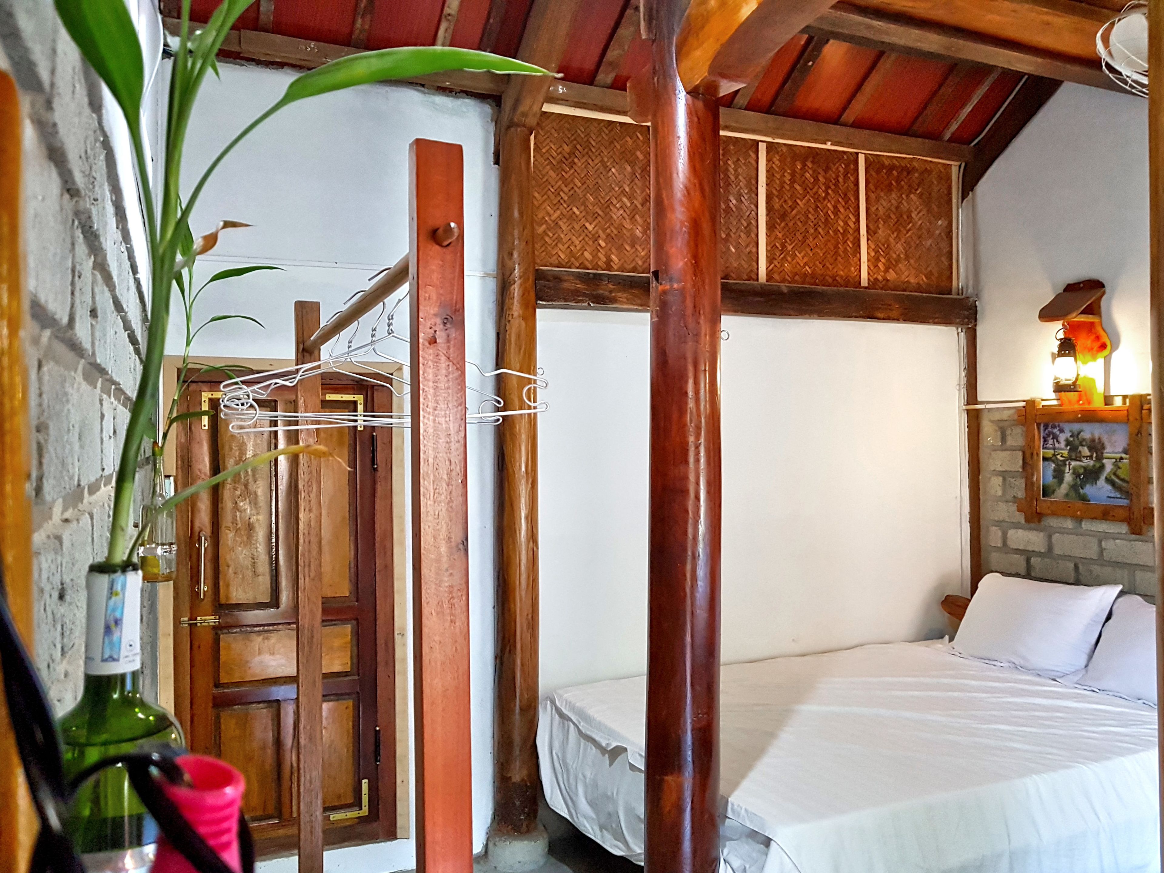 A bedroom with a wooden bed, a hanging plant, and a wooden door.