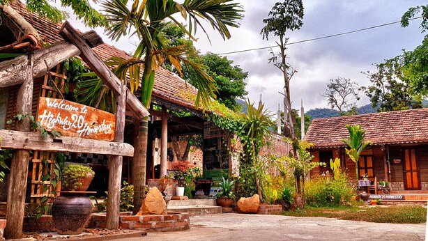 Um edifício rústico com uma placa de boas-vindas aos hóspedes na Highway 20 Homestay.