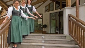 A staircase with wooden railings and a stone floor, leading to a building with large windows and a glass door. - Hotel Rainhof (Senales)