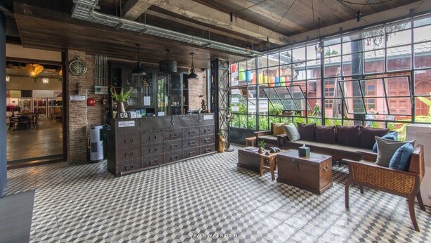 Un vestíbulo espacioso con piso a cuadros, una recepción y un gran ventanal con vistas al exterior.
