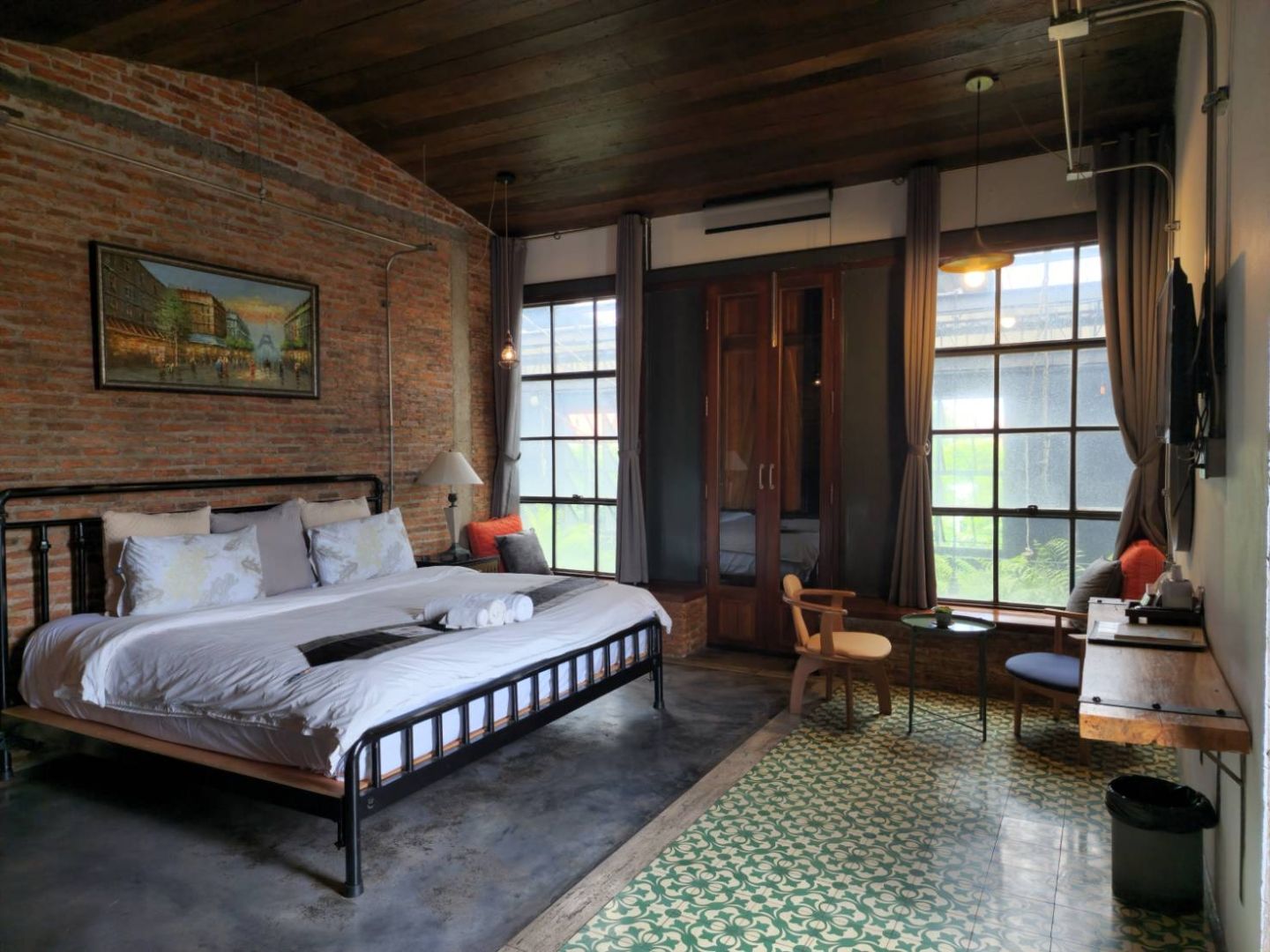 A room with a bed, a chair, a desk, a window, and a painting on the wall.