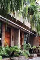 Un edificio con fachada de ladrillo, puertas de madera grandes y helechos colgantes.