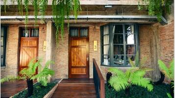 A rustic building with two wooden doors, numbered 2 and 3, and a window with curtains.