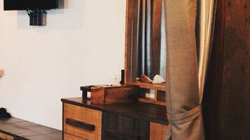 A wooden dresser with drawers, a mirror, and a television mounted on the wall.