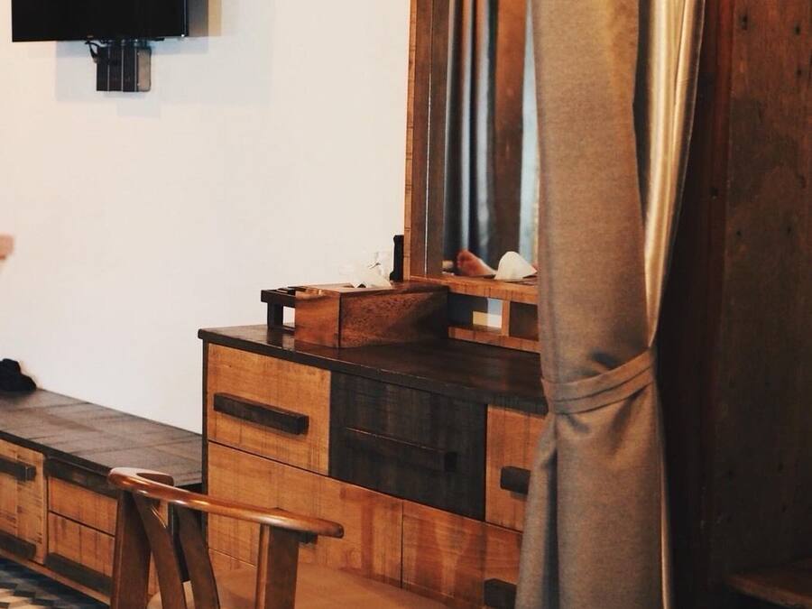 A wooden dresser with drawers, a mirror, and a television mounted on the wall.