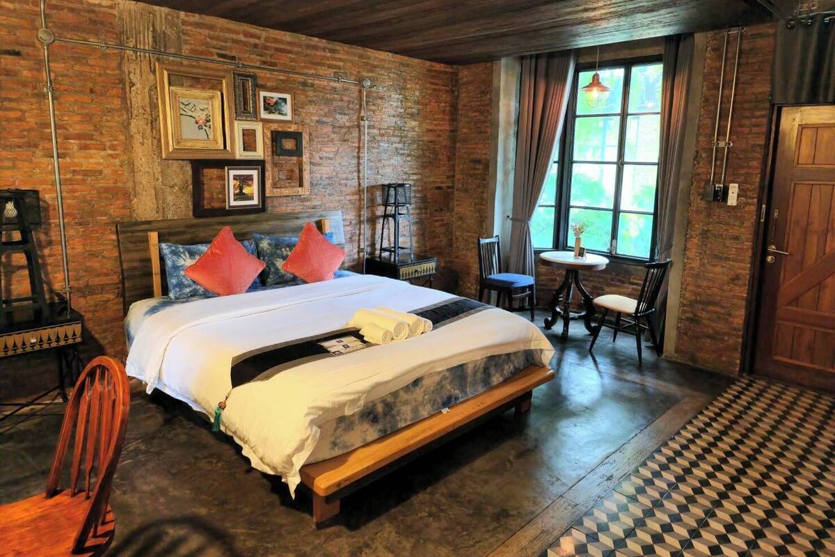 A rustic room with a wooden bed, a small round table, and a chair.