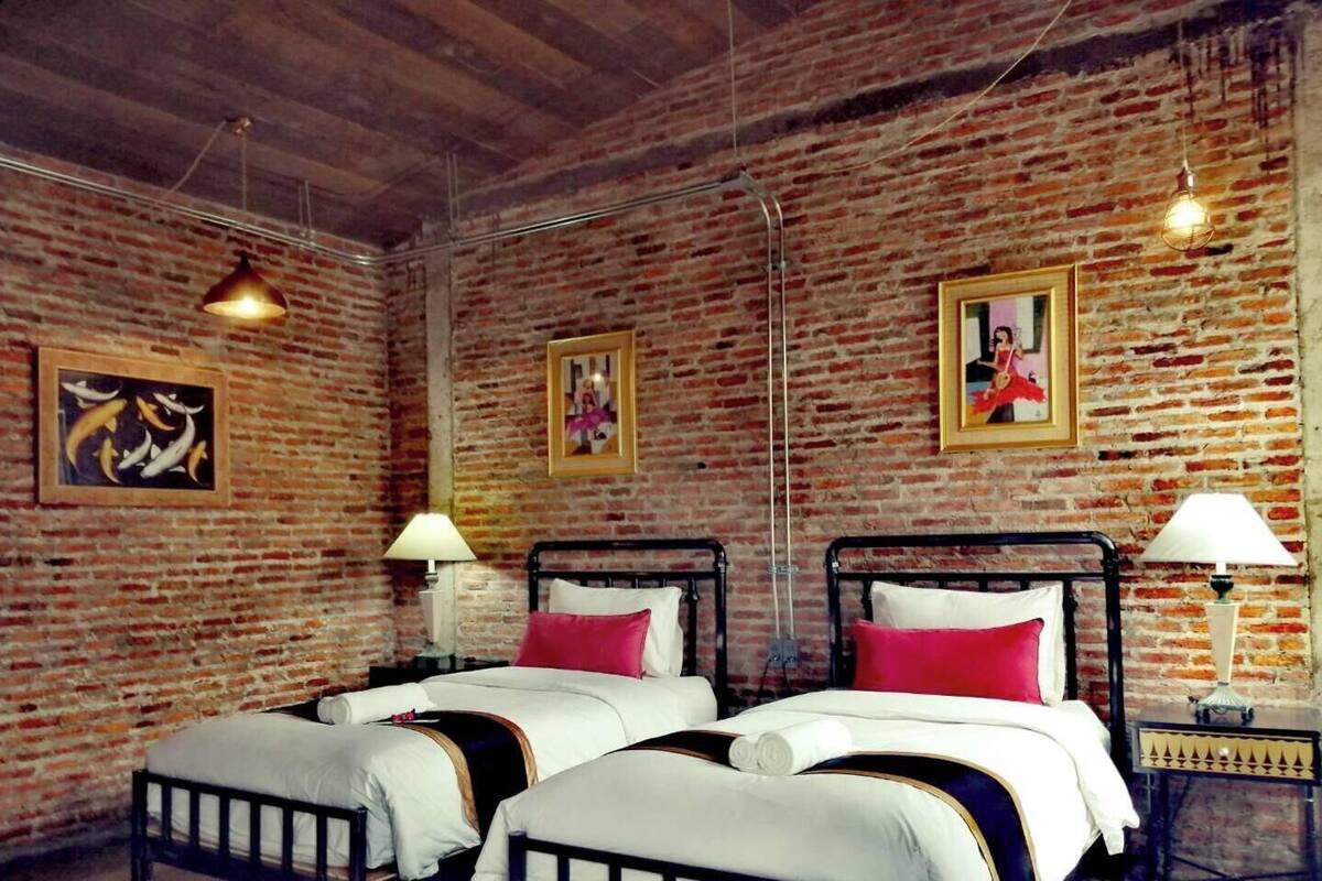 A room with two beds, brick walls, and hanging light fixtures.