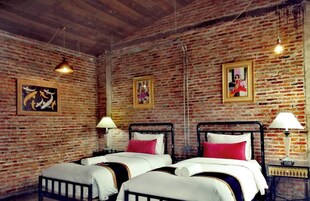 A room with two beds, brick walls, and hanging light fixtures.