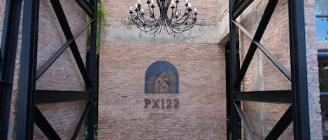 Un edificio de ladrillo con una gran reja metálica y un letrero que dice 'PX122'.