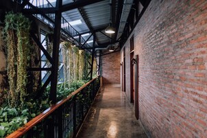 Un pasillo con paredes de ladrillo, barandilla de madera y plantas colgantes.