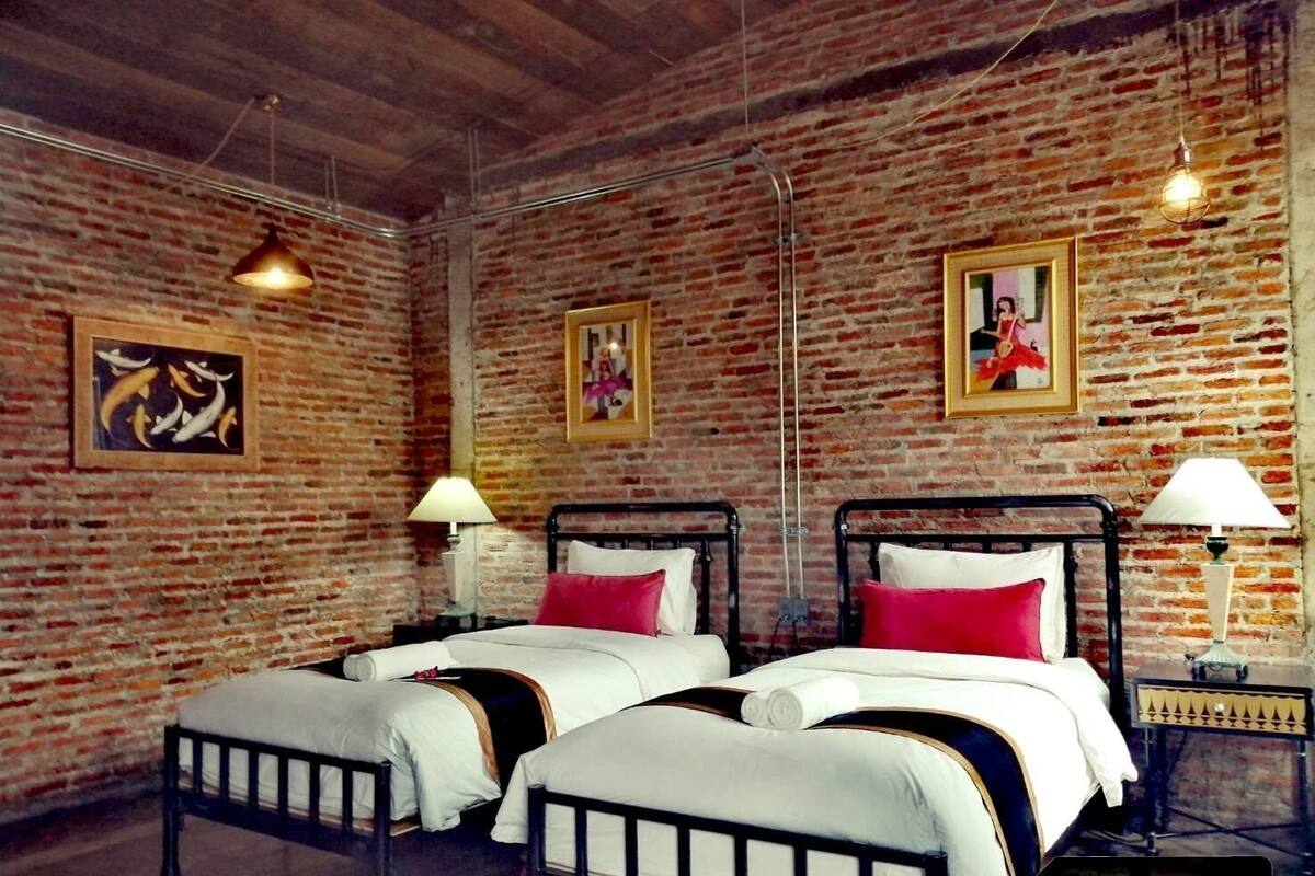 A room with two beds, brick walls, and hanging light fixtures.