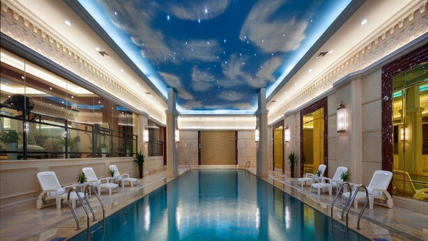 A large indoor swimming pool with a starry sky ceiling, surrounded by lounge chairs and columns. - Chongqing Auwi Hotel (Chongqing)