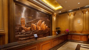 A reception desk with a large decorative wall, columns, and a marble floor. - Chongqing Auwi Hotel (Chongqing)