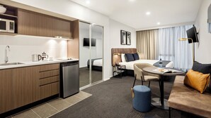 A modern hotel room with a kitchenette, a bed, a seating area, and a TV. - Quest Maribyrnong (Maribyrnong)